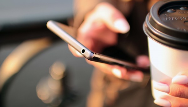 Hand holding phone and coffee